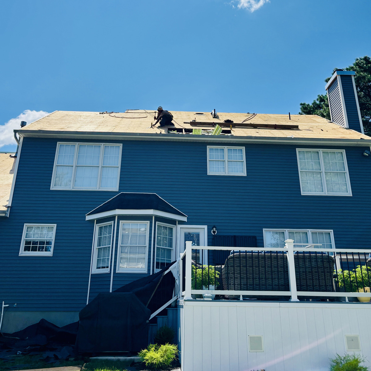 Fresh roof decking on a blue Jersey Shore home mid-job