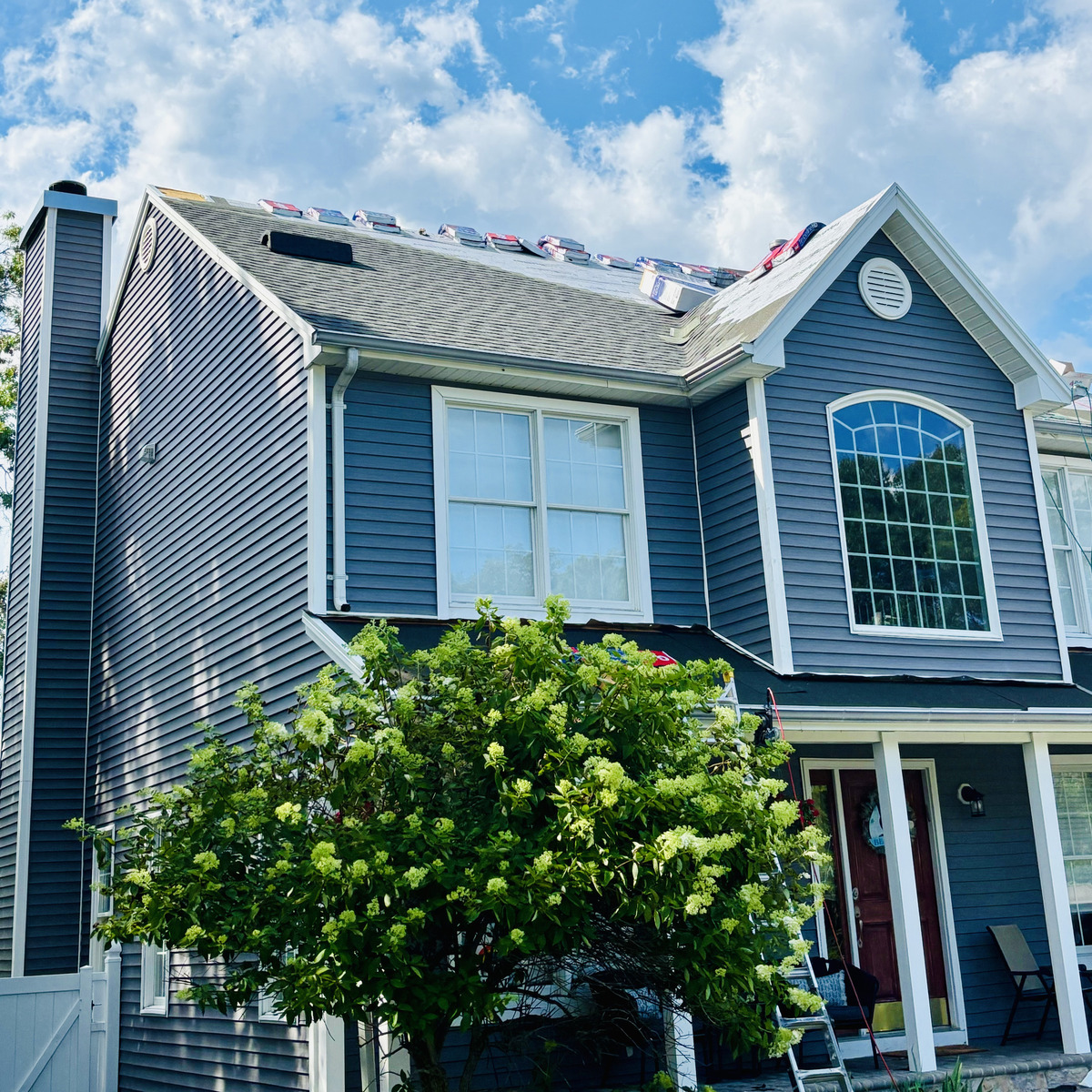Shingle bundles staged along the ridge on a shore home roof replacement
