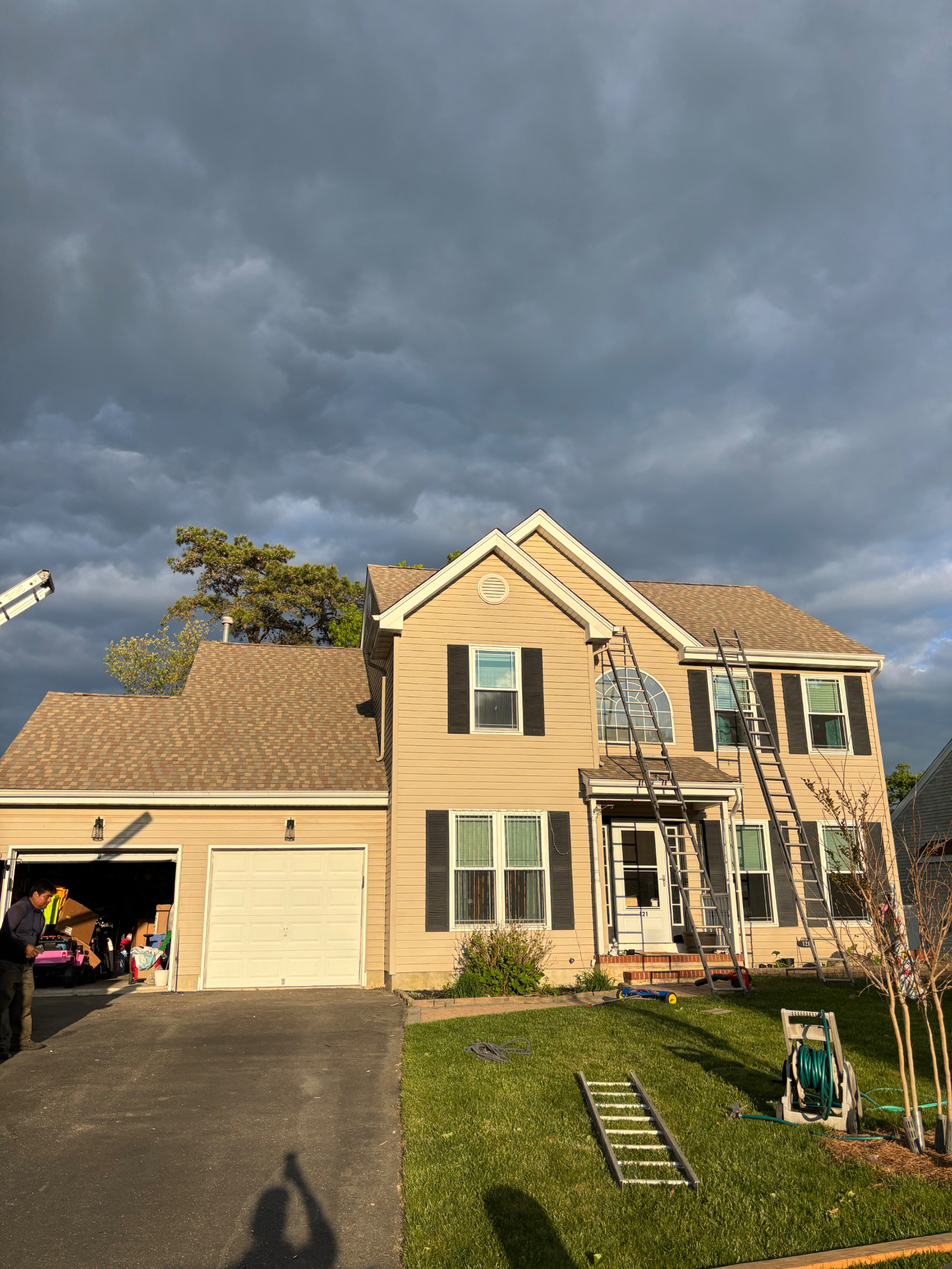Roddy Roofing crew mid-roof-replacement with ladders under a dramatic sky